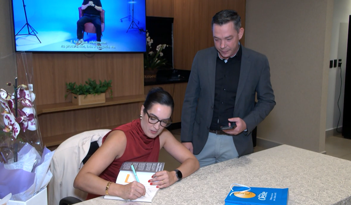 Delegada Aline Sinnott autografando seu livro "A Jornada dos Esquecidos" em evento em Campo Grande.