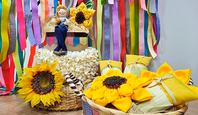 Cesta com itens típicos de festa junina, como paçoca, canjica e pipoca, com destaque para a pesquisa de preços em Campo Grande.