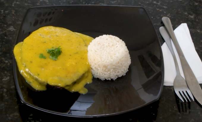 Posta de pintado grelhado com creme de manga ao lado de arroz.